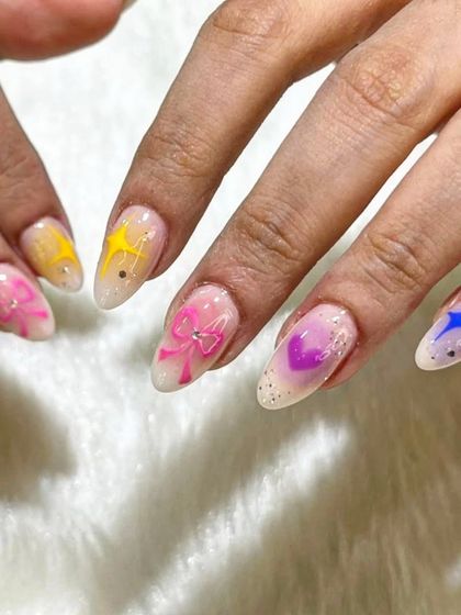 A close-up of the aura nails, showing the delicate 3D bow and the soft blend of colors.