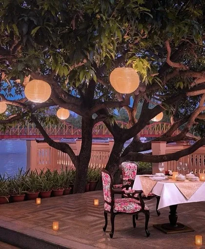 A romantic alfresco dining spot at IHCL Pilibhit-Haridwar, designed for intimate moments. The elegant, floral-patterned chair and soft lighting create a storybook setting by the pool.