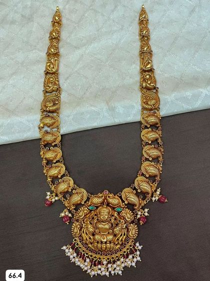 A beautiful 92.5 silver gold-plated haram with a mango-shaped design along the chain. The large central pendant features a Goddess Lakshmi, surrounded by colorful stones and pearls.