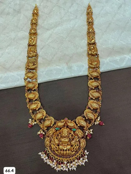 A beautiful 92.5 silver gold-plated haram with a mango-shaped design along the chain. The large central pendant features a Goddess Lakshmi, surrounded by colorful stones and pearls.