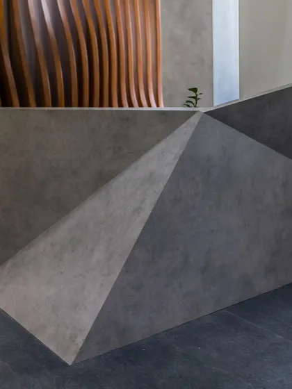 The reception desk at the 'Acutely Bare' office is a sculptural piece made of faceted concrete. It sets the tone for a workspace that is both raw and highly designed.