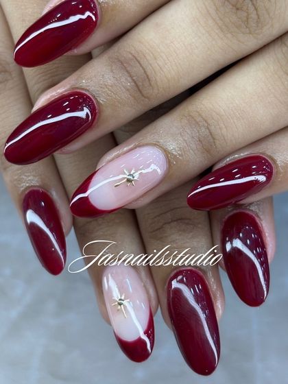 A close-up of the elegant maroon and nude nail set. The star charm is a subtle but beautiful detail.