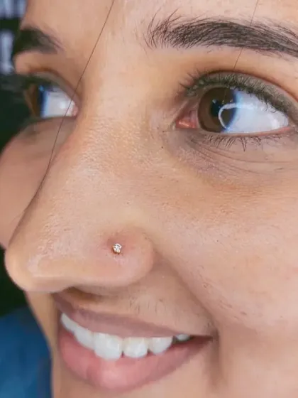 A close-up of a delicate, sparkling nose stud. This is a popular choice for a first nose piercing, and I ensure the placement is neat and flattering.