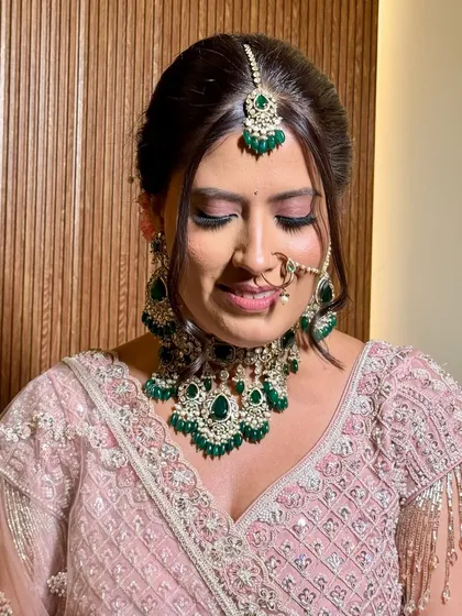 A close-up of the bride's soft, romantic makeup. The pink tones on her eyes and the emerald jewellery create a stunning contrast.