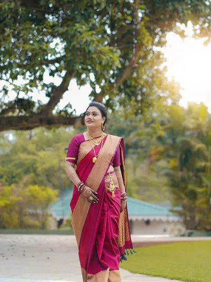 A full-length shot of the bride walking through a park. This photo captures the grace of her movement and the beauty of her traditional paithani saree in a natural setting.