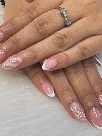 A modern twist on a timeless classic. This look combines a clean French manicure with delicate marble art and a hint of gold glitter for an elegant and sophisticated finish.
