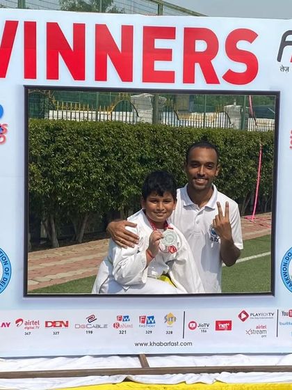 A student and coach pose in the winner's frame after a silver medal win.
