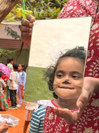A moment of pure, uninhibited joy. A child sees her own reflection with a freshly painted face during our Children's Day carnival, a day we dedicate to celebrating the unique magic and spirit of childhood.