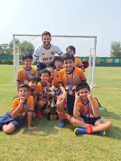 All smiles after a successful tournament. The team gathers for a photo with their coach and their well deserved trophy.