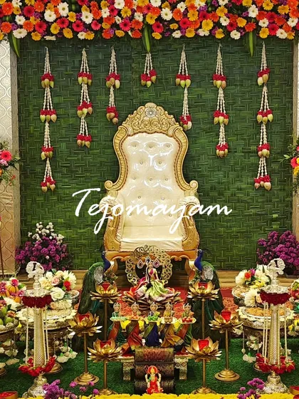 A baby shower setup with a backdrop of woven banana leaves and hanging flower garlands, creating a very traditional and natural look.