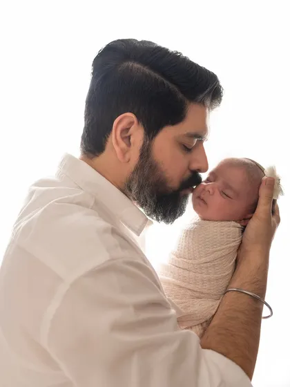 A father's gentle kiss on his newborn baby's forehead. A simple, powerful portrait showing the instant bond and love.
