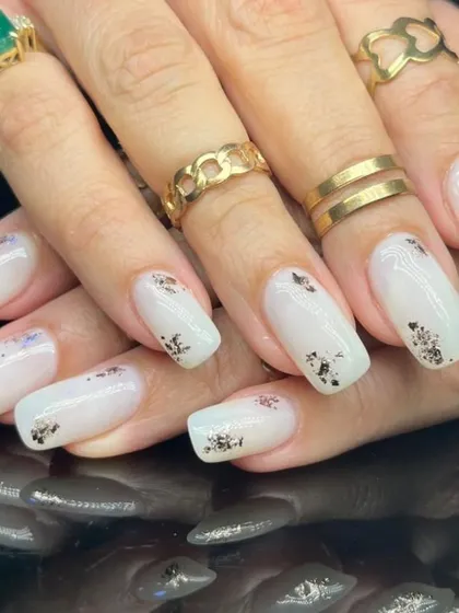 A side view of the elegant white and silver foil manicure.
