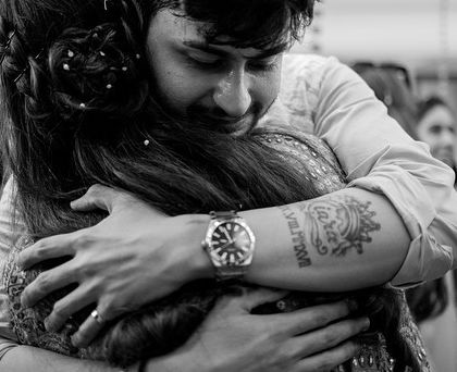 A groom's emotional hug, a moment of vulnerability and love. This candid black and white photo focuses on the raw feeling and the strong bond being expressed.