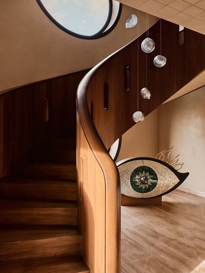 A view of the sculptural staircase and the eye-shaped art piece, capturing the interplay of curves, materials, and artistic expression that defines this home's unique character.
