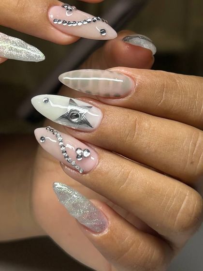A stunning set of festive nail art. This design on long stiletto nails includes silver star accents, sparkling glitter, and delicate rhinestone chains for a glamorous holiday look.