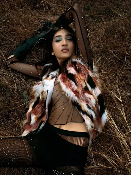 Another reclining pose, this time with a focus on the model's expression and the details of her sparkling bodysuit. The natural setting provides a beautiful, rustic contrast.