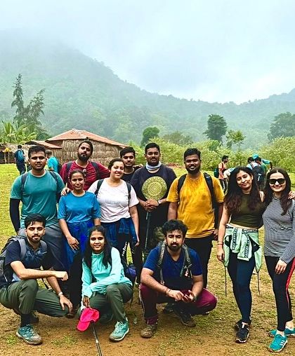 A group of trekkers at the start of a trail, with a rustic homestay in the background. This captures the beginning of an exciting rural adventure.