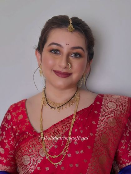 The complete look, featuring a traditional red Banarasi saree with a contrasting blue shela. The makeup is balanced to harmonize with the rich colors of her outfit.