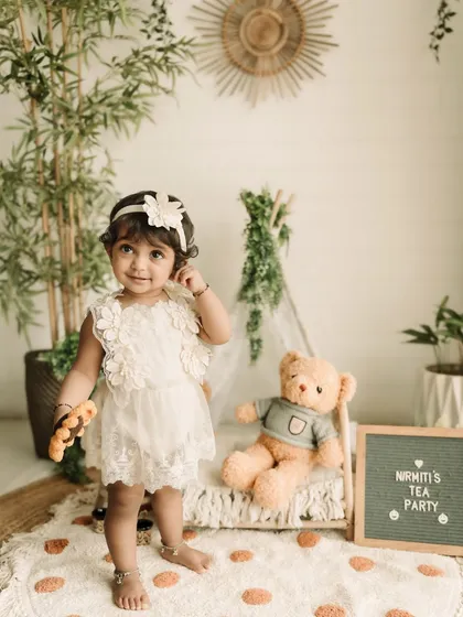 A sweet one-year-old girl enjoying her tea party-themed milestone session in the studio.