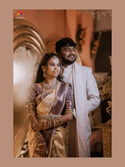 A candid and happy reception portrait. The couple's genuine smiles and the grand decor in the background perfectly capture the celebratory atmosphere.