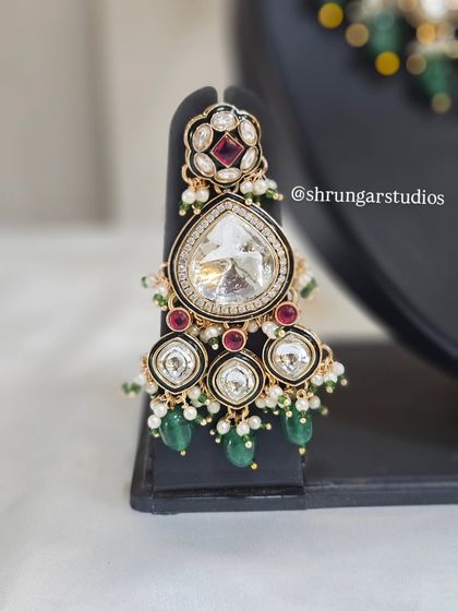 A close-up of a stunning earring from a Kundan and AD bridal set, featuring a large central stone.