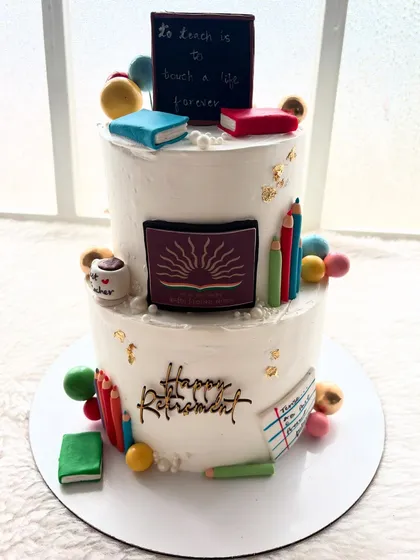 A two-tier retirement cake for a beloved teacher. The design includes a chalkboard, books, and pencils to celebrate a long and impactful career.