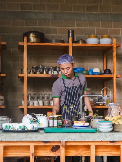 Behind every successful event is a meticulous preparation process. Here, one of our chefs is getting everything ready in our open kitchen, surrounded by fresh ingredients and traditional cookware, ensuring every dish is perfect.