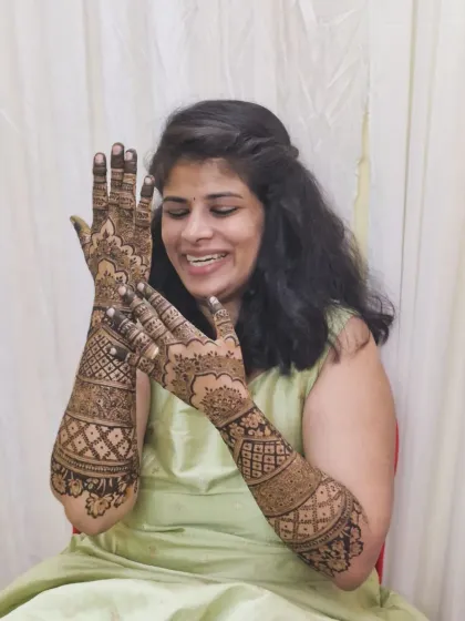A candid shot of the bride admiring her detailed mehendi design, a mix of geometric and floral patterns.