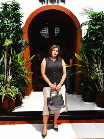 A chic lunch look with a black button-up vest and a cream-colored skirt, accessorized with a black handbag.