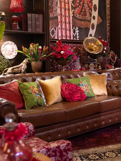 The heart of the lounge area is this classic brown leather Chesterfield, which I styled with a vibrant collection of velvet and embroidered cushions in jewel tones to add a pop of color and texture.