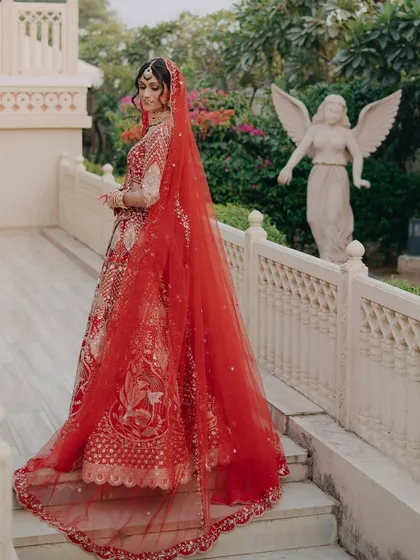 The dramatic trail of the red dupatta creates a stunning visual. The bride's entire look is styled to be photogenic and grand.