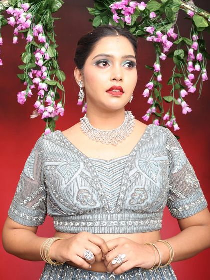 This close-up shows the detail in the blouse and how the makeup complements the cool tones of the outfit.