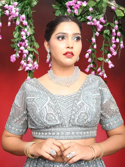 This close-up shows the detail in the blouse and how the makeup complements the cool tones of the outfit.