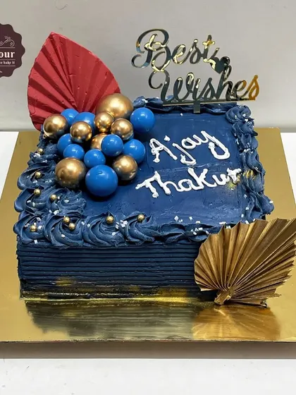 A retirement cake for a corporate event. This vanilla lotus biscoff cake has a rich blue design with gold accents, offering best wishes for a new chapter.