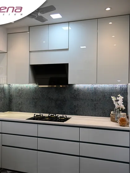 This premium kitchen design uses a sophisticated palette of light grey and a dark patterned backsplash. The handle-less drawers and cabinets create a clean, uninterrupted look, which is a hallmark of modern kitchen interiors.