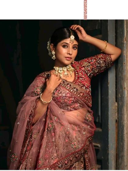 A stunning bridal portrait. The model is wearing a deep wine-colored lehenga with a matching jewellery set, creating a complete and royal look.