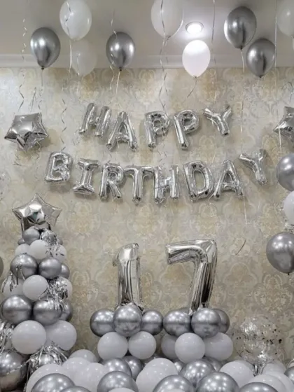 A silver and white themed room decoration for a 17th birthday. The setup includes a balloon tree, number foils, and "Happy Birthday" letters for a festive look.