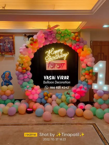 A colorful first birthday celebration with a hint of Frozen magic. This setup features a vibrant balloon ring, a custom neon sign with the name 'Jija' in Marathi, and a character cutout of Elsa.