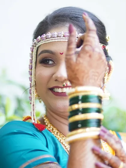 A creative pose highlighting the bride's green bangles and her beautiful smile. The focus is on the joy and tradition of the wedding day.