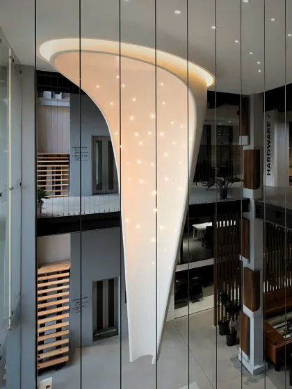 A striking interplay of scale, light, and sculptural form. This custom light installation cascades through a double-height commercial showroom, designed to elevate the spatial experience and inspire a sense of wonder.