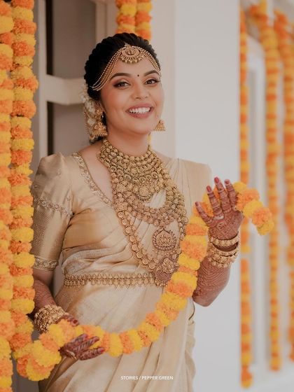 The bride posing with a marigold garland, her smile and traditional attire creating a vibrant and happy portrait.