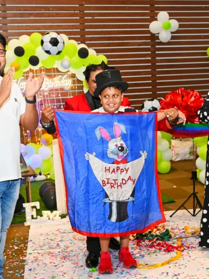 A magical moment from a birthday magic show, with the birthday boy holding a 'Happy Birthday' banner that appeared out of thin air.