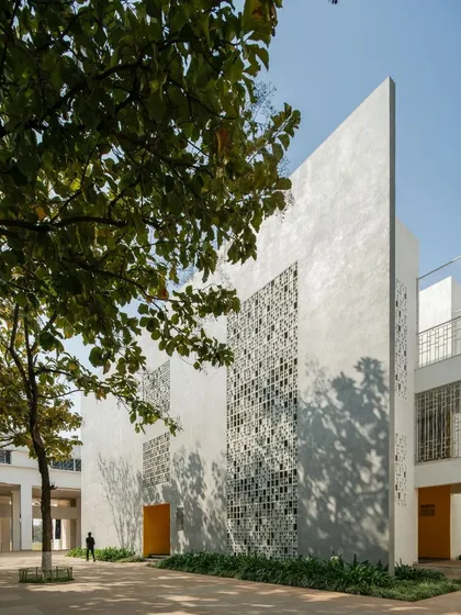 A corner view of Vidyashilp Academy, where a solid wall meets a perforated one. The design plays with solid and void, creating a visually dynamic composition that is also highly functional in its response to the climate.