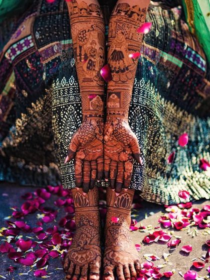 A classic bridal shot, with the bride's hands and feet adorned with intricate henna and surrounded by flower petals.