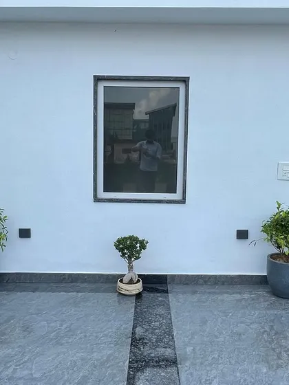 A minimalist entrance design featuring two ficus plants in grey pots flanking a small bonsai tree. This simple, symmetrical arrangement creates a calm and elegant welcome.