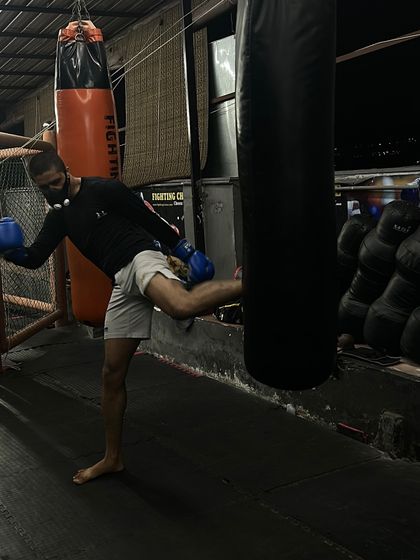 Practicing a roundhouse kick on the heavy bag. This drill strengthens the hips and refines the technique for maximum impact in a kickboxing or MMA context.