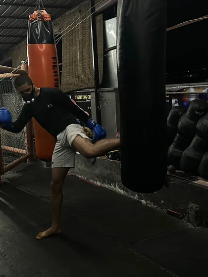 A fighter practices a teep, or front kick, on the heavy bag. This is a fundamental technique in Muay Thai used to control distance and disrupt an opponent's rhythm.