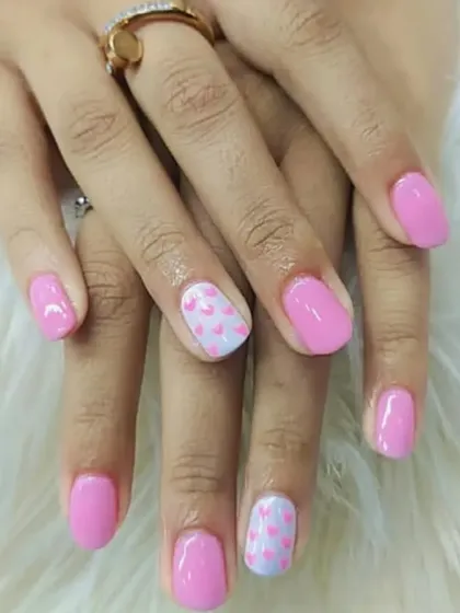 A sweet and simple design featuring a soft pink gel polish with accent nails that have a delicate pattern of tiny hearts. This is a perfect example of a subtle yet charming manicure.