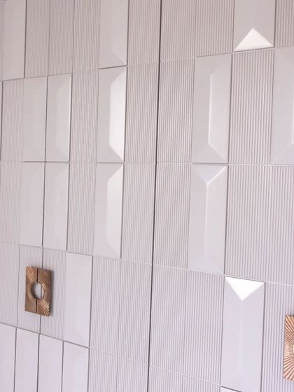 The interplay of light and shadow on the 3D-paneled shutters creates a dynamic effect, making this wardrobe a focal point in any room.