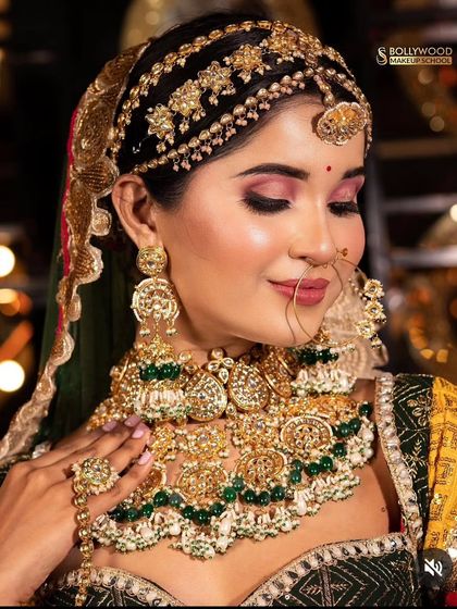 A bride showcasing a heavy Punjabi-style choker with a unique mathapatti. The green and gold combination is a classic for bridal wear.